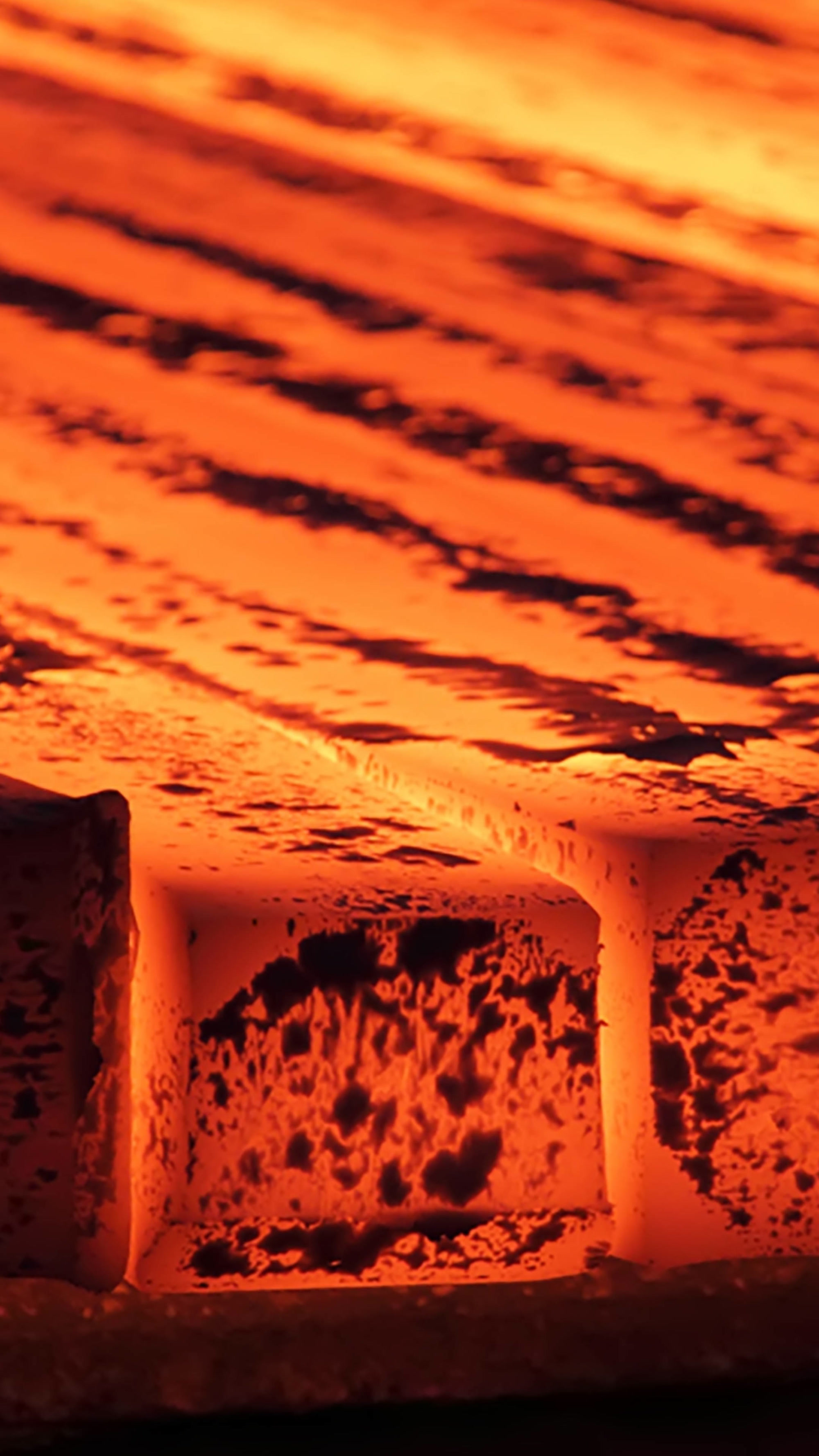 An image of a set of red hot metal beams laying in a row.